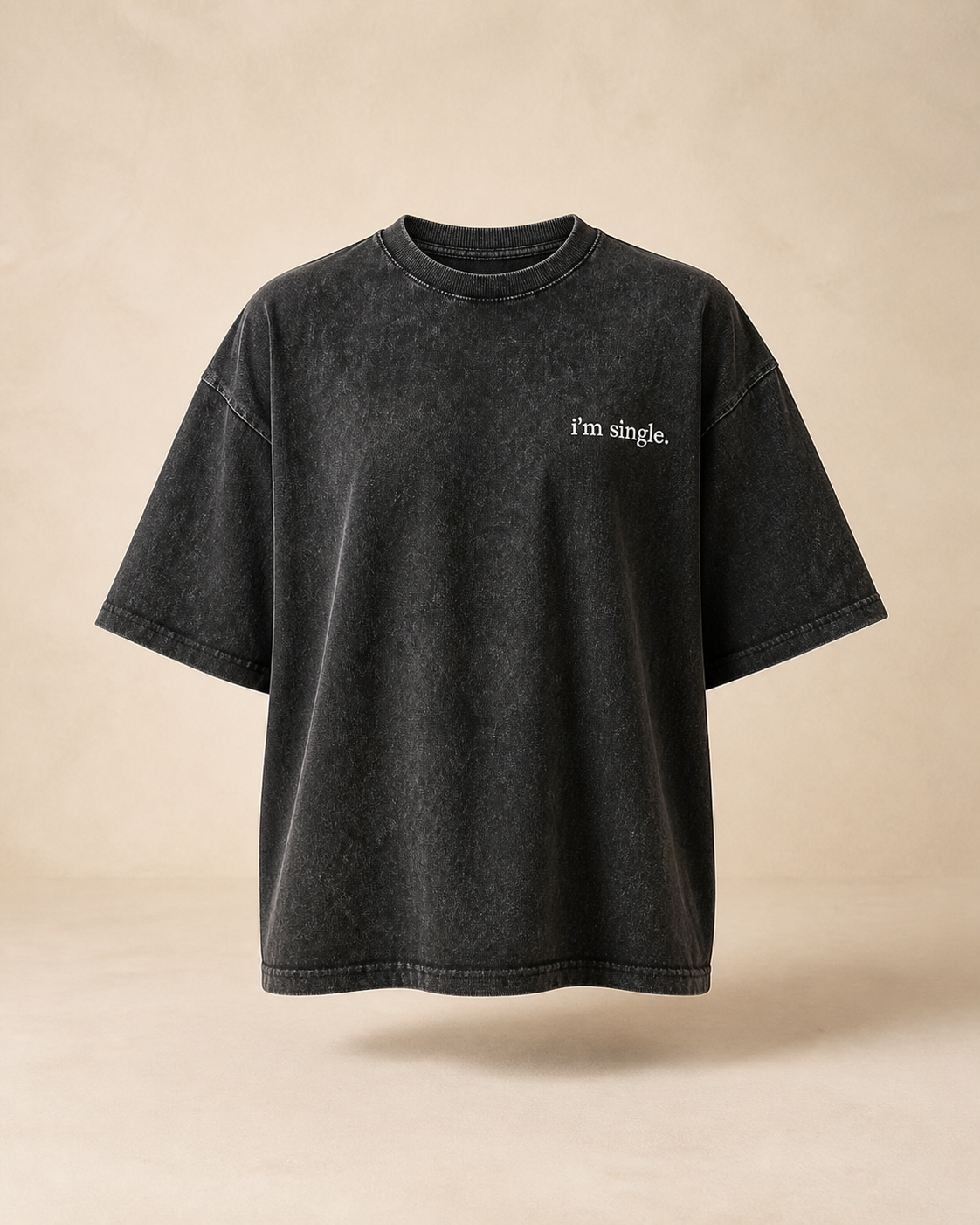A black mineral-wash short-sleeve t-shirt with 'I'm single.' printed in white on the left chest, displayed against a warm beige background.