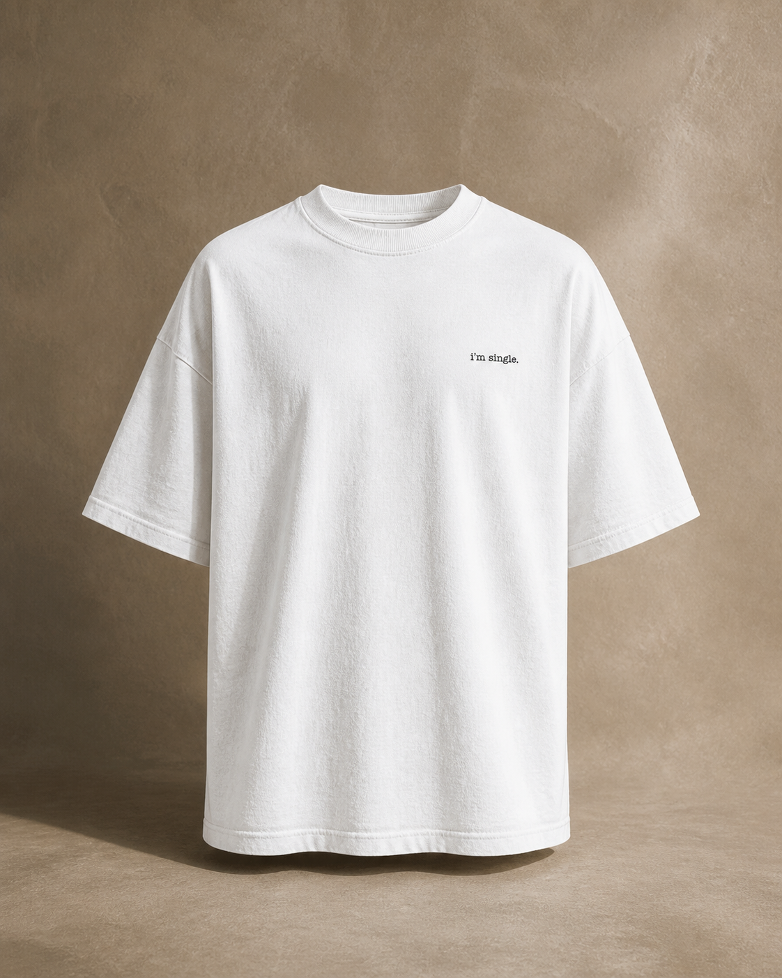 A white short-sleeve t-shirt with 'i'm single.' printed in black on the left chest, displayed against a warm beige background.