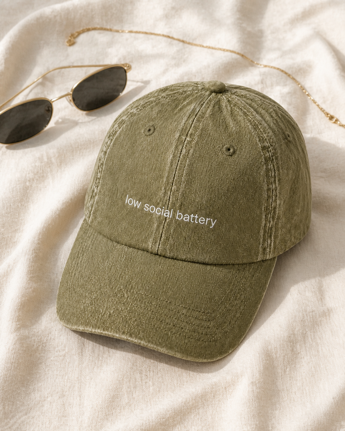 Low Social Battery cap in olive green — washed cotton dad hat with “low social battery” embroidered in white, product shot