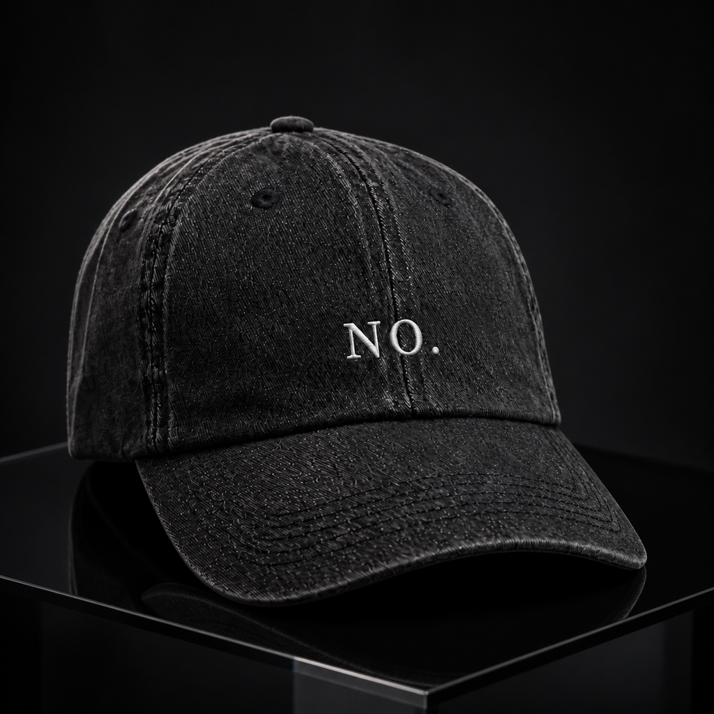 The washed black 'NO.' cap on a reflective black pedestal against a black backdrop.