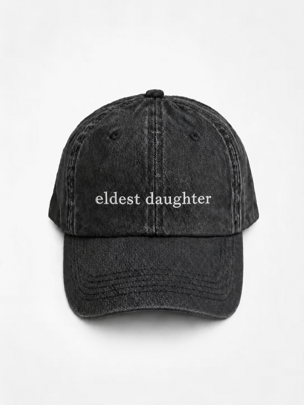 HERO-BLACK Washed black six-panel baseball cap with 'eldest daughter' embroidered in white serif lettering across the front, shown face-on against a plain white background.