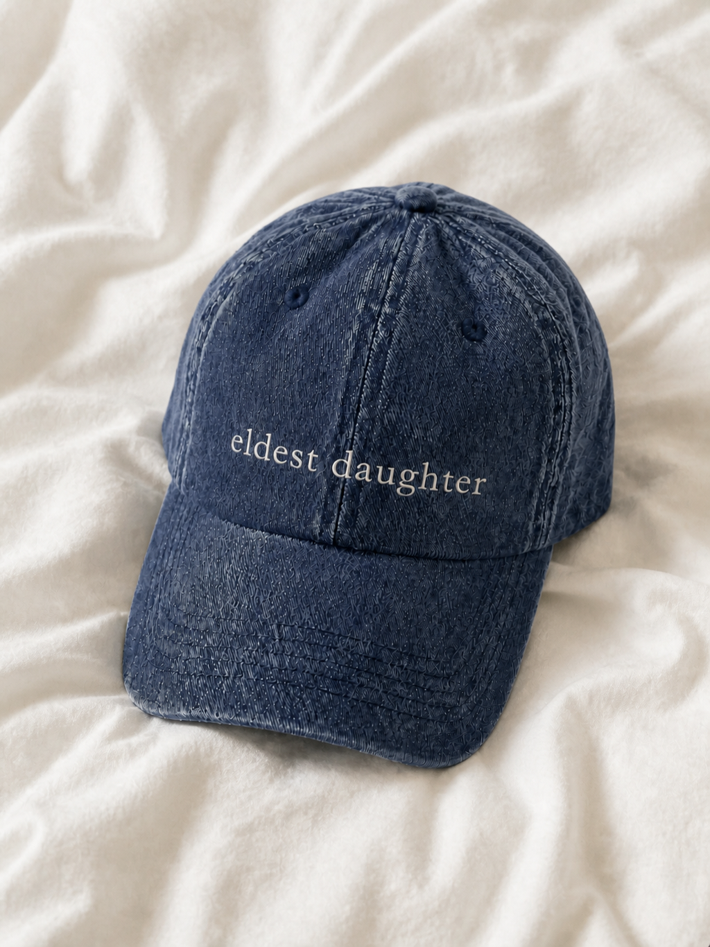 Washed navy 'eldest daughter' cap resting on rumpled cream linen.
