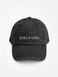 HERO-BLACK Washed black six-panel baseball cap with 'GIRL'S GIRL' embroidered in white serif capitals across the front, shown face-on against a plain white background.