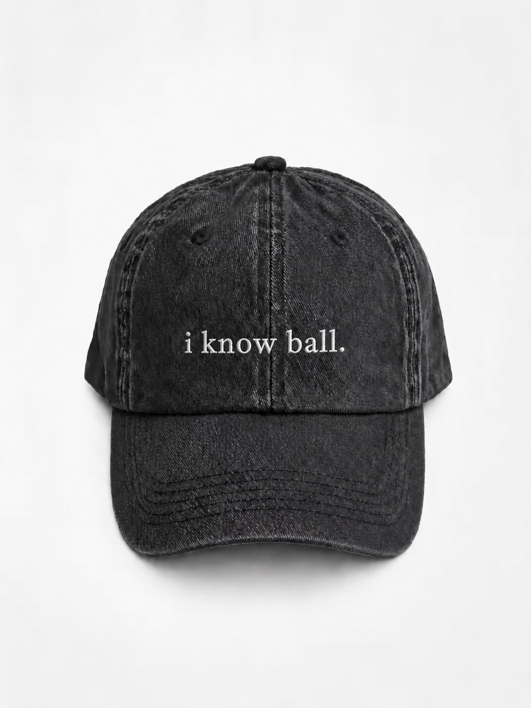 HERO-BLACK Washed black six-panel baseball cap with 'i know ball.' embroidered in white serif lettering across the front, shown face-on against a plain white background.