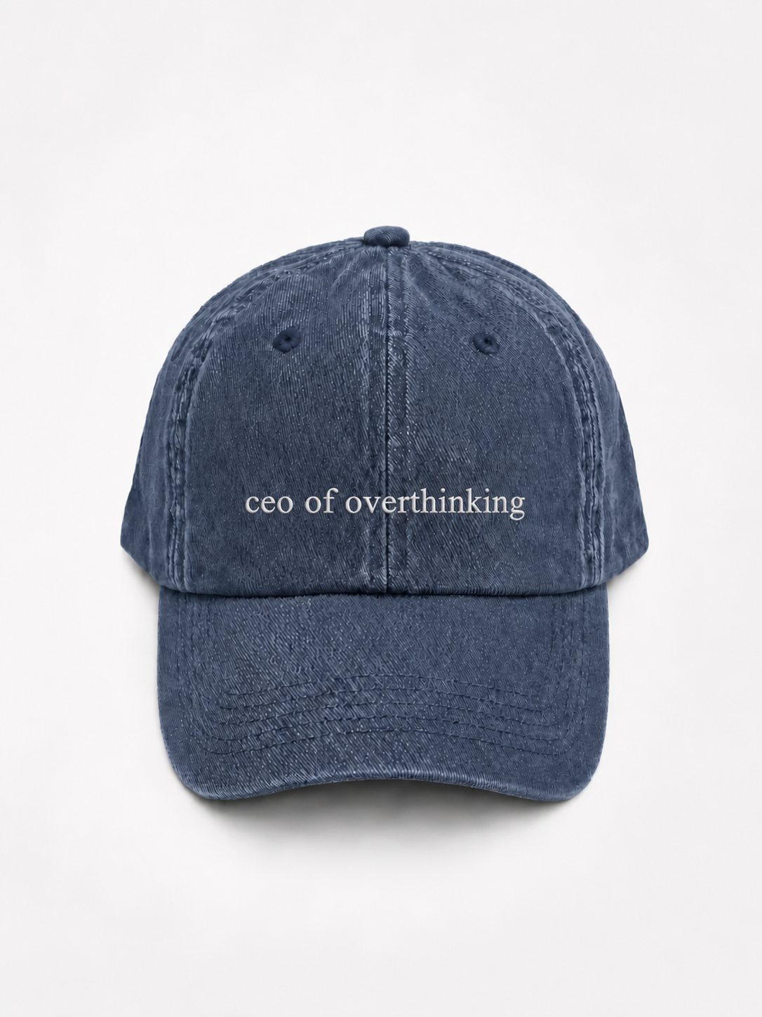 The washed navy 'ceo of overthinking' cap photographed flat and front-on, showing the white embroidered lettering across the front panel.