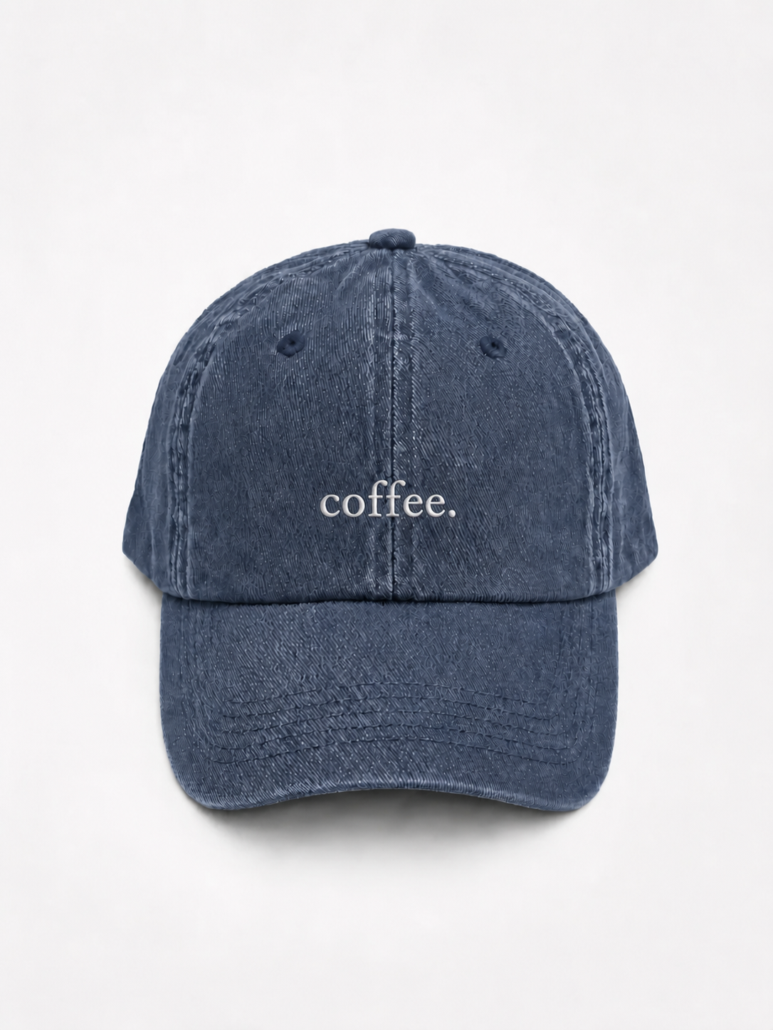 The washed navy 'coffee.' cap photographed flat and front-on, showing the white embroidered lettering across the front panel.