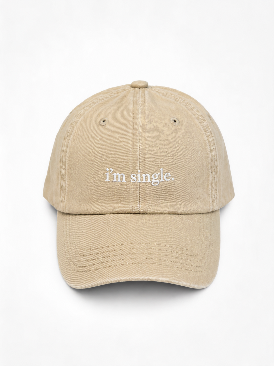 A beige baseball cap with the phrase 'i'm single.' embroidered in white lowercase serif text on the front, shown against a plain white background.
