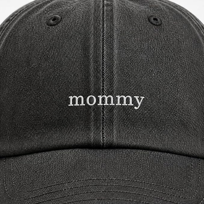 A close-up of a black dad hat with the word 'mommy' embroidered in white lowercase letters on the front panel.