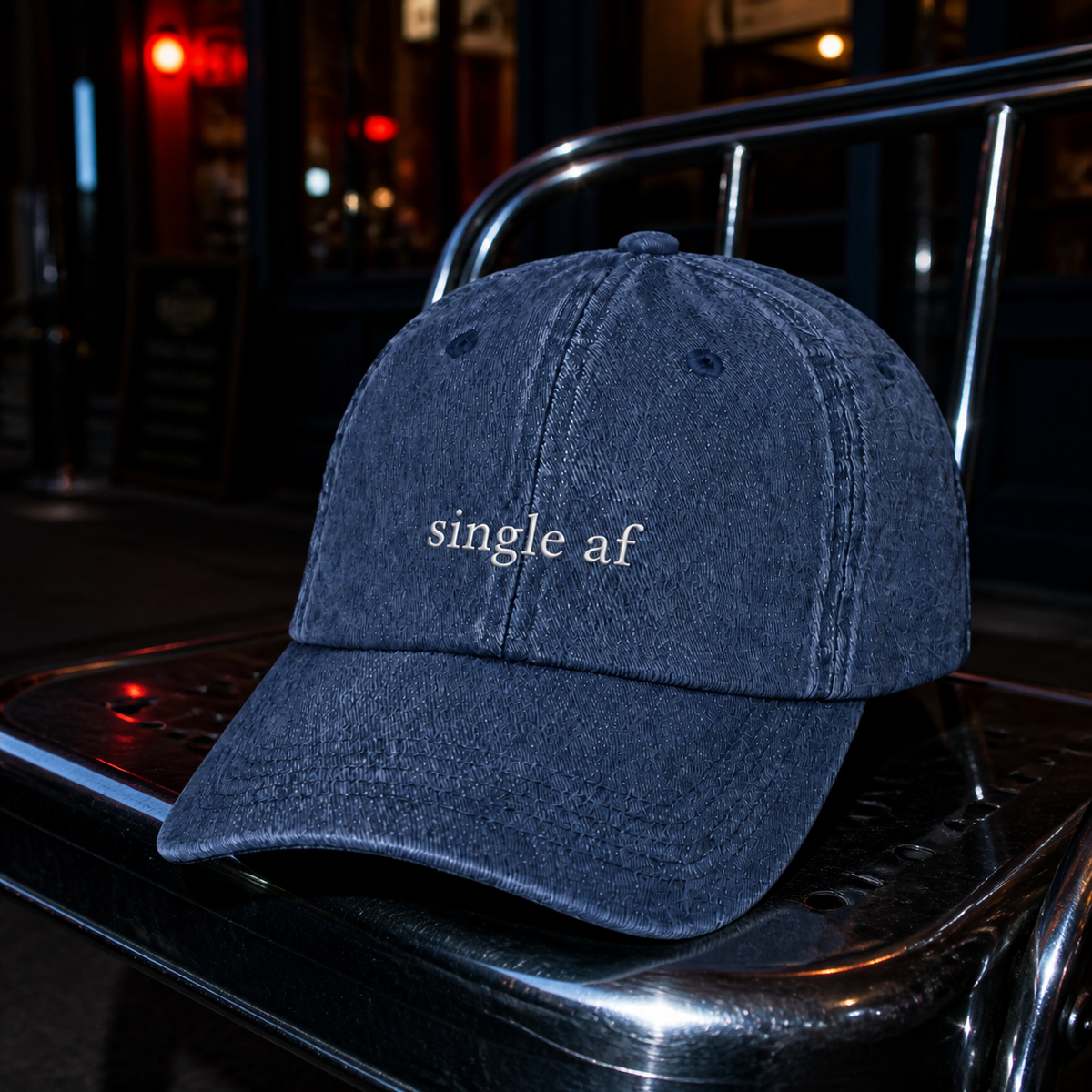 A navy baseball cap embroidered with 'single af' in white, photographed at night with direct flash.