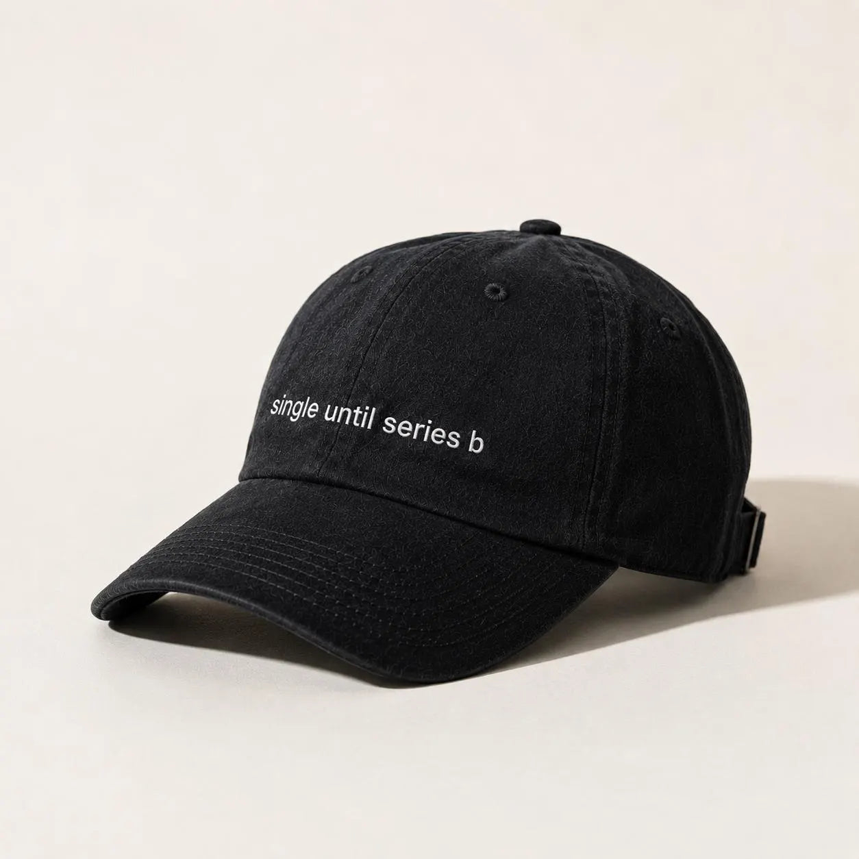 A black cotton baseball cap with white embroidered text reading 'single until series b' on the front, photographed on a clean off-white background.